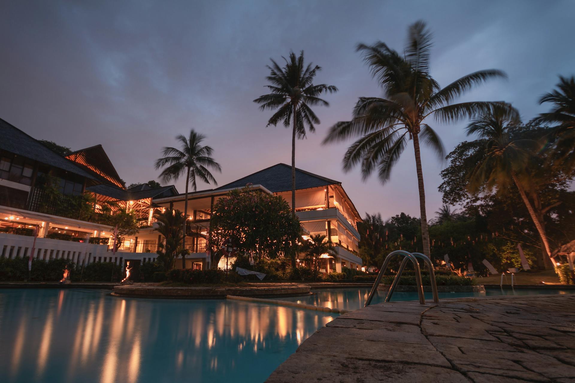 Luxury resort landscaping with palm trees and pool at twilight